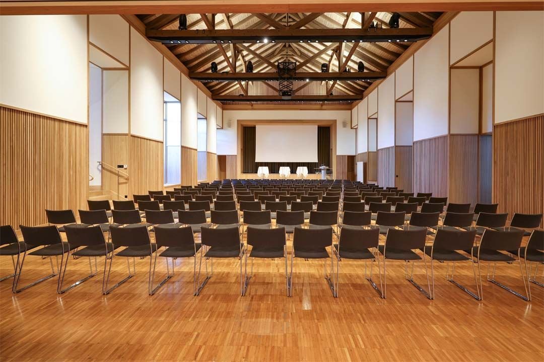 Der Kleine Saal im SAL in Schaan mit Konzertbestuhlung, Blick auf Bühne und Leinwand, offene Dachkonstruktion mit Holzbalken